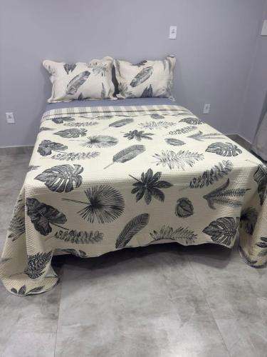 a bed with a black and white blanket and pillows at Suíte Doce Recomeço da Alice in Arraial do Cabo