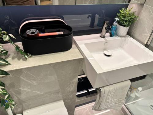 a bathroom with a white sink with a knife in a briefcase at Luxury 2BR- Sleeps 5- Westfield Apartment- 3 min to station- Perfect for Families Shopping in London