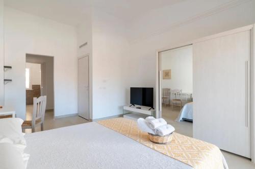 Habitación blanca con espejo grande y TV en I Centenari Longevity Rooms, en Lotzorai