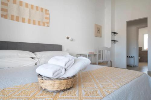 1 dormitorio con una cesta de toallas en la cama en I Centenari Longevity Rooms, en Lotzorai