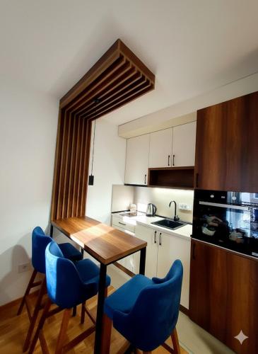 a kitchen with a wooden table and blue chairs at Apartman Felicita 2 Zlatibor in Zlatibor