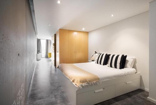a bedroom with a large white bed and a hallway at Aveiro Urban Apartment by Visit-Aveiro in Aveiro