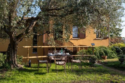 a table and chairs under a tree in front of a house at Uliveto Moriondo in Salò