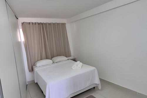 ein weißes Schlafzimmer mit einem Bett und einem Fenster in der Unterkunft Apartamento beira-Mar em Natal in Natal