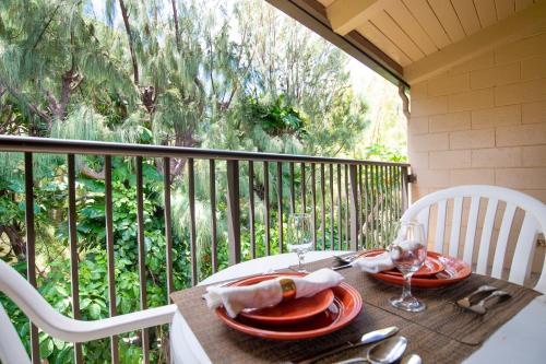 a table with plates and wine glasses on a balcony at Hono Kai C12 in Maalaea