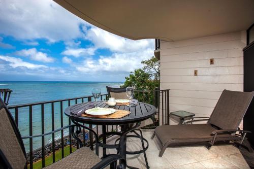 a balcony with a table and chairs and the ocean at Kahana Reef 321 in Kahana