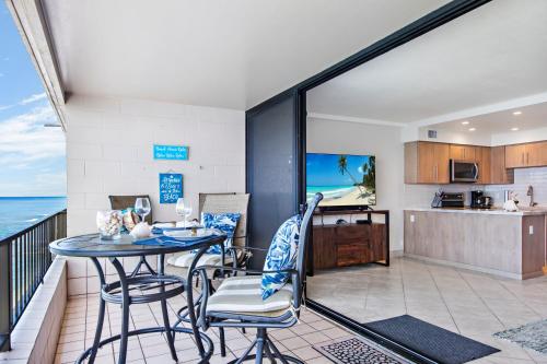 a balcony with a table and chairs and a kitchen at Maui Kai 504 in Kahana
