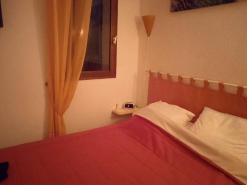 une chambre avec un lit avec une couverture rouge et une fenêtre dans l'établissement Le Barcarès, au Barcarès