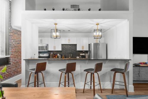 a kitchen with a bar with four stools at West End Loft - Downtown 5 min walk to River St in Savannah