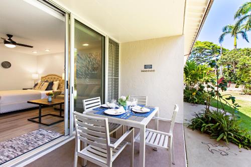ein Esszimmer mit einem Tisch und Stühlen auf einer Terrasse in der Unterkunft Napili Puamala 128 in Kahana