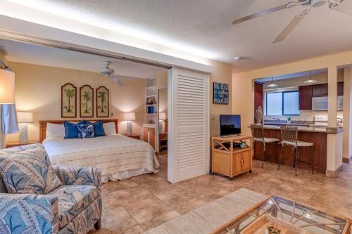 a bedroom with a bed and a living room at Hono Kai A16 in Wailuku