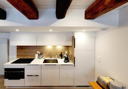 a kitchen with white cabinets and a sink at Le clos du prieuré - Les Gîtes de la Côte d'Amour in Batz-sur-Mer