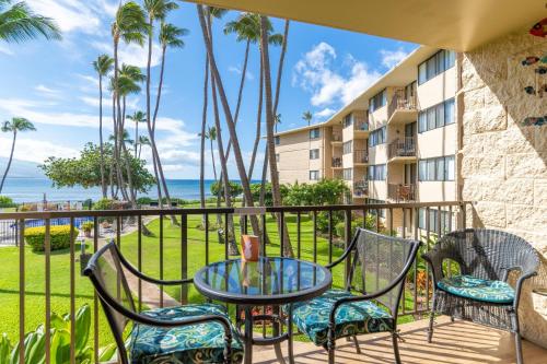 a balcony with a table and chairs and a view of the ocean at Kanai A Nalu 210 in Wailuku