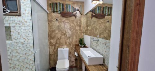 a bathroom with a white toilet and a sink at Home 013 in São Vicente