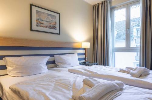 Ferienwohnung Deichperle - Ihr idyllischer Rückzugsort an der Ostsee in Zingst في زنغست: غرفة فندق بها سريران ونافذة