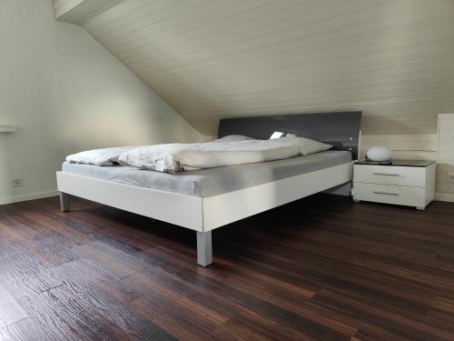 a bedroom with a white bed and a wooden floor at Goldiger Berg - Pilatusweg 6 in Affoltern