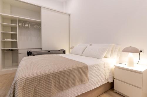 a white bedroom with a large bed and a lamp at Loft moderno recién reformado con patio en el centro de Elche in Elche