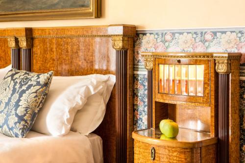 a bed with a wooden headboard and a basket with apples on it at Castello Di Spessa - Residenze d'epoca in Capriva del Friuli
