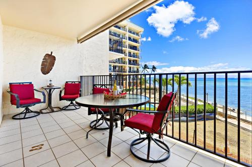 a balcony with a table and chairs and the ocean at Hololani A203 in Kahana