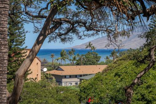 ein Haus auf einem Hügel mit dem Ozean im Hintergrund in der Unterkunft Maui Vista 2414 in Kihei