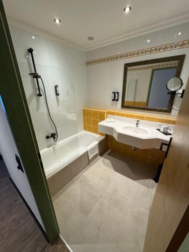 Un baño con lavabo, bañera y espejo. en Self-Check-in Hotel VinoQ Mistelbach, en Mistelbach
