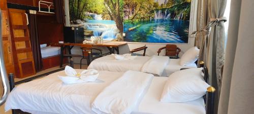 two beds in a room with a painting on the wall at Batikseafood Airport & Room in Nai Yang Beach