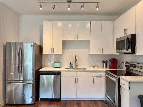 a kitchen with white cabinets and a stainless steel refrigerator at Brand-new Parkview with Balcony in Old Fourth Ward 542Blvd in Atlanta