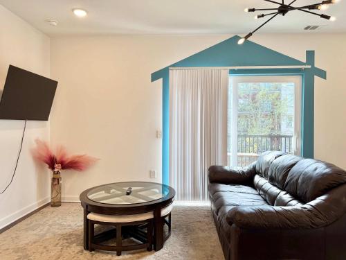 a living room with a leather couch and a table at Brand-new Parkview with Balcony in Old Fourth Ward 542Blvd in Atlanta