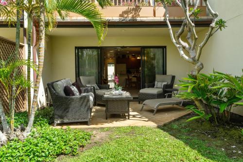 a patio with wicker chairs and a table at Maui Kamaole K104 in Wailea
