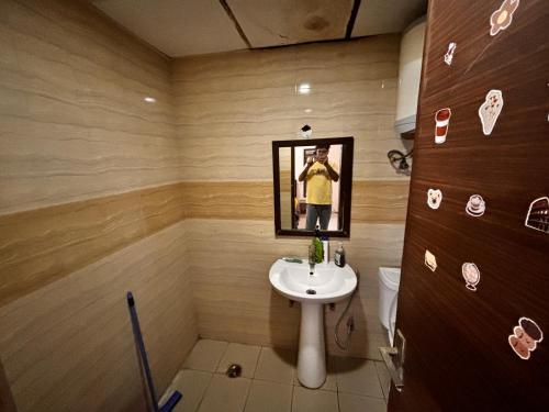 a man taking a picture of a bathroom with a sink at The night view in Noida