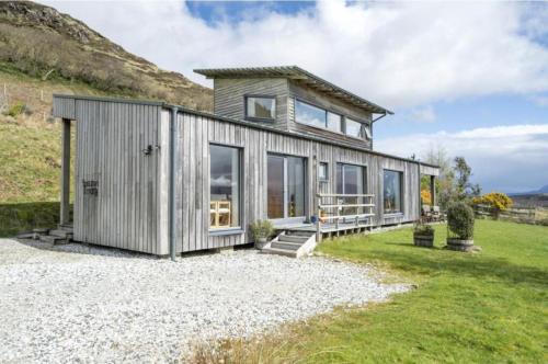 a tiny house on a gravel lot with mountains in the background at Speuran Mora in Saasaig