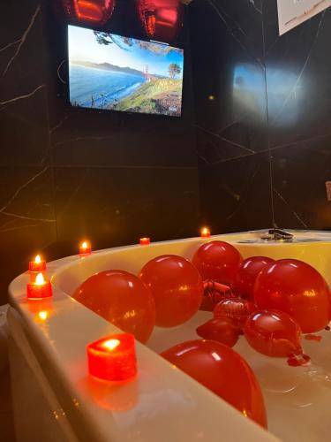 Un baño con velas rojas en una bañera con televisor. en Hotel Iris, en Varcaturo