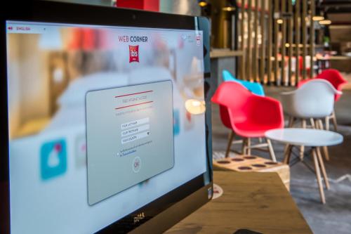 a computer monitor sitting on a table with chairs at Ibis Szczecin Centrum in Szczecin