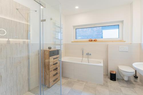 a bathroom with a tub and a toilet and a sink at Sund Huus in Altefähr
