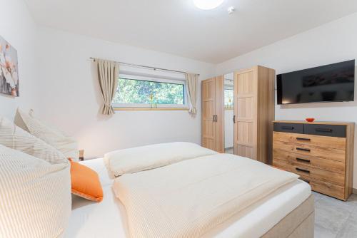 a white bedroom with a bed and a television at Sund Huus in Altefähr