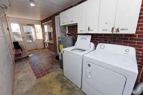 una lavatrice e asciugatrice in una stanza con muro di mattoni di The Copper Cottage on Main ad Abbeyville