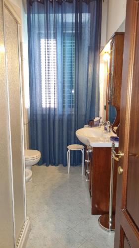 a bathroom with a sink and a toilet and blue curtains at Assisi - Appartamento Maristella in Santa Maria degli Angeli