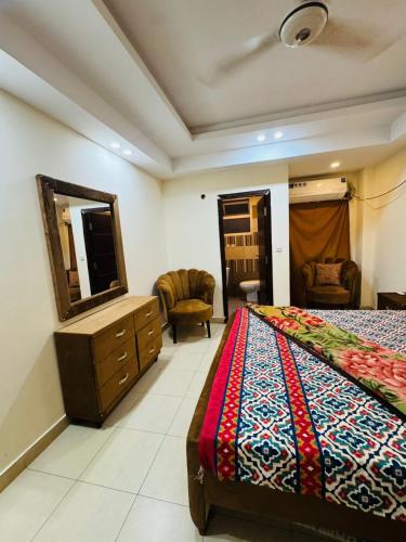 a bedroom with a bed and a dresser and a mirror at Syed Apartment 104 in Islamabad