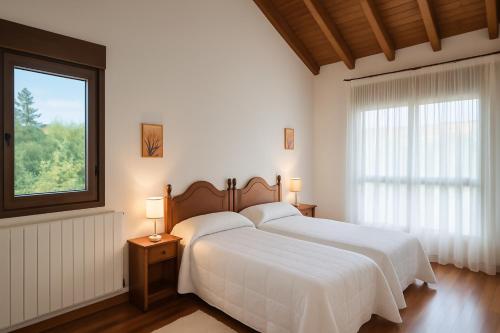 una camera con due letti bianchi e una finestra di Casa vacacional La Vicoca a Poo de Llanes