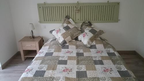a bedroom with a bed with a quilt on it at Gîte de l'hamelinaie in Montanel