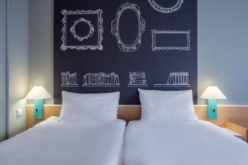 two beds in a room with a wall with drawings on it at Ibis Szczecin Centrum in Szczecin