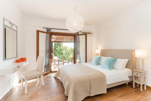 ein weißes Schlafzimmer mit einem Bett und einem Tisch und Stühlen in der Unterkunft Avlaki Bay House in Arvanitakaíïka