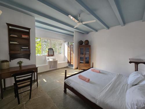 a bedroom with a bed and a desk and a ceiling at Beachside in Anjuna