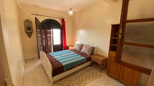 a small bedroom with a bed and a door at Gypsy Surf Maroc Hostel in Tamraght Ouzdar