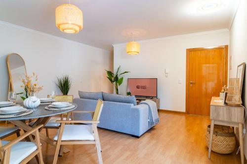 een woonkamer met een blauwe bank en een tafel bij GuestReady - The perfect hideout in Caniço in Caniço