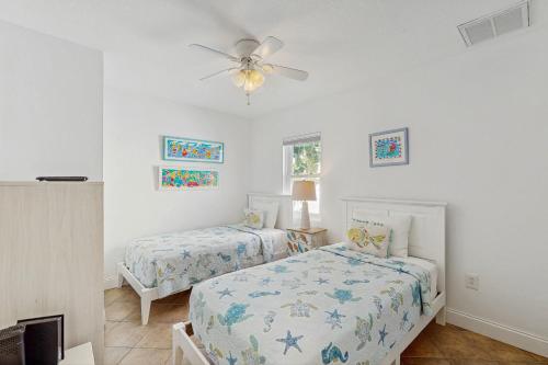 een slaapkamer met twee bedden en een plafondventilator bij Sea's The Day in Anna Maria