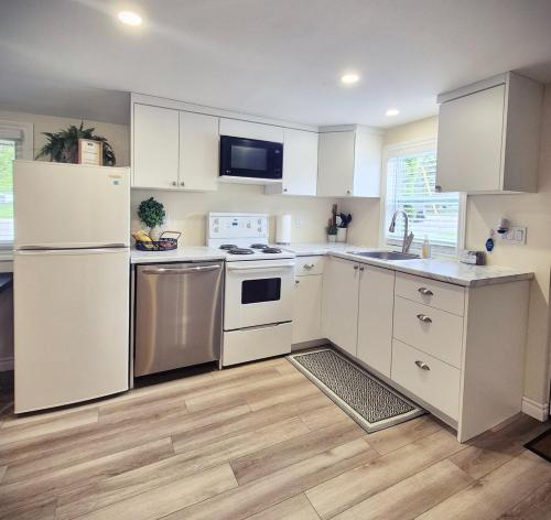 una cucina con elettrodomestici bianchi e mobili bianchi di Parkview Boho Cottage 5 - Cedar Serenity a Leamington