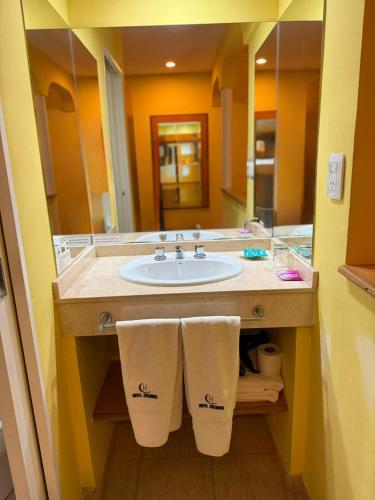 a bathroom with a sink and a mirror at Hotel Colonos in Las Grutas