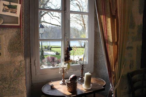 a table with a candle in front of a window at Les Vergnes in Saint-Pardoux-le-Neuf