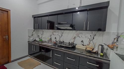 una cocina con armarios negros y encimeras de mármol en APV Home, en Trincomalee